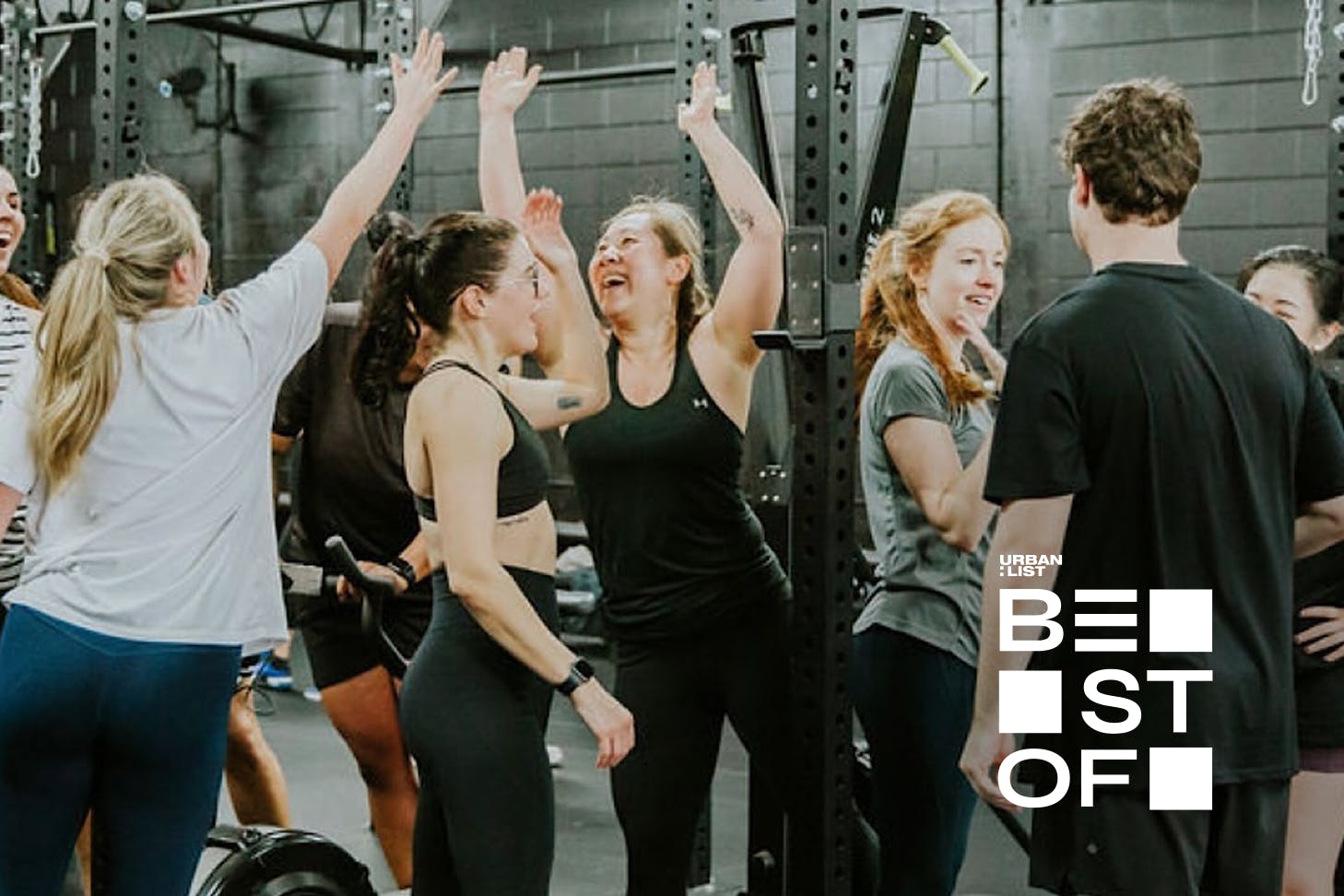 A bunch of happy people high five after a workout at Lift Club, one of Auckland's best gyms.